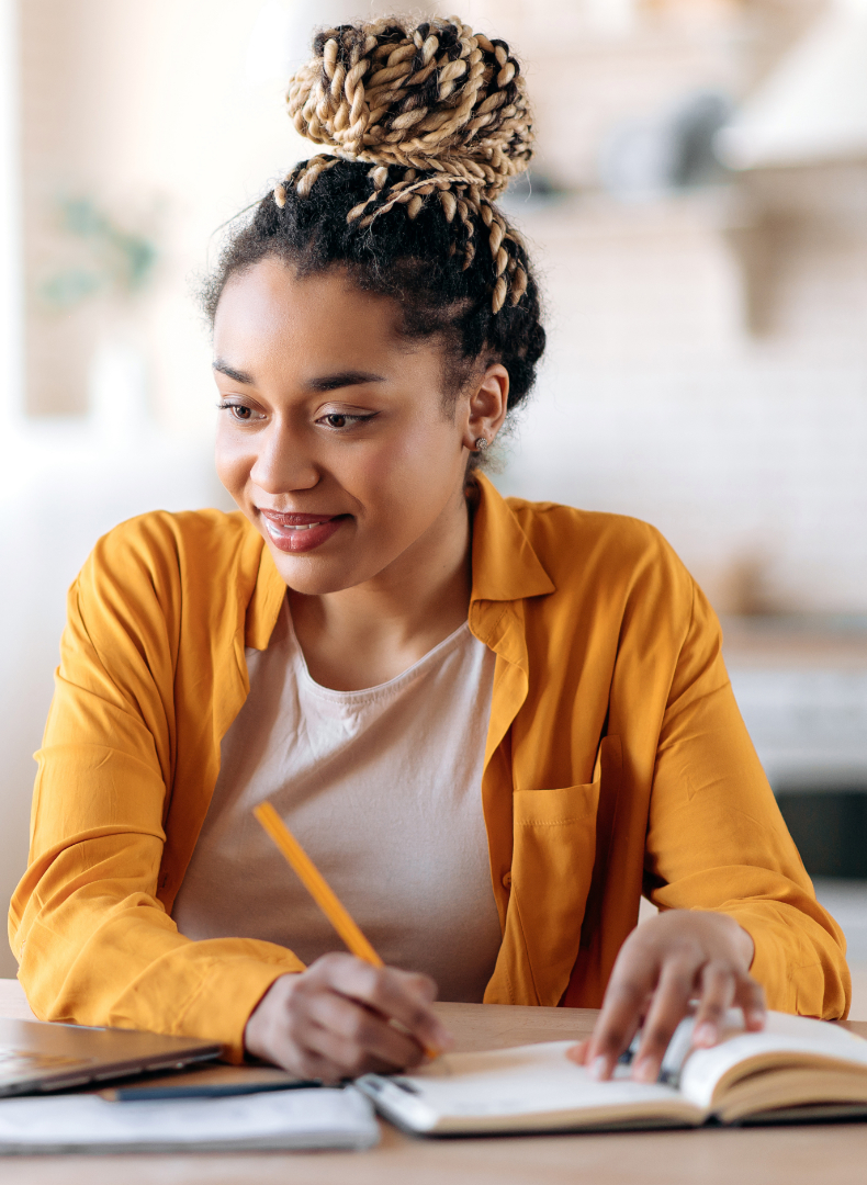 A student sitting at a desk, writing in a notebook